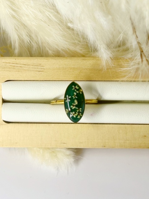 Ręcznie robiony pierścionek z kwiatami zatopionymi w żywicy, regulowany, w kształcie markizy, na ekspozytorze.