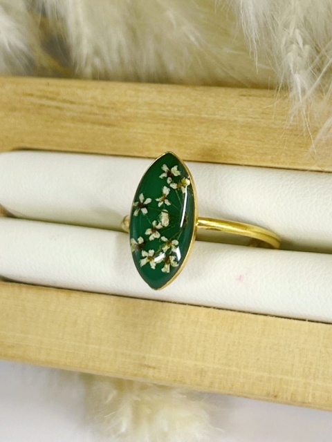 Biżuteria z żywicy – złoty pierścionek regulowany z naturalnymi białymi kwiatami na zielonym tle.